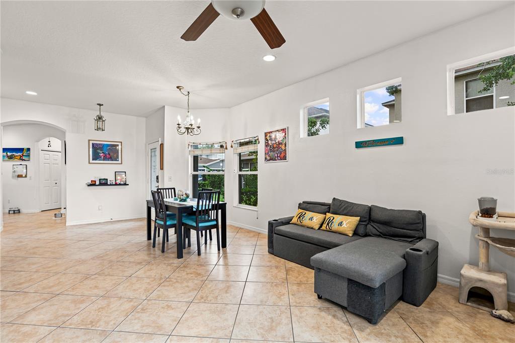 A living and dining area features tile flooring, a gray sectional sofa, and a dining set — 1121 TRAVERTINE TERRACE, SANFORD, FL