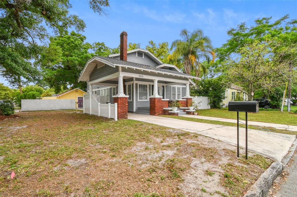 A gray bungalow with a brick-based front porch and a concrete driveway — 6810 N NAVIN AVENUE, TAMPA, FL