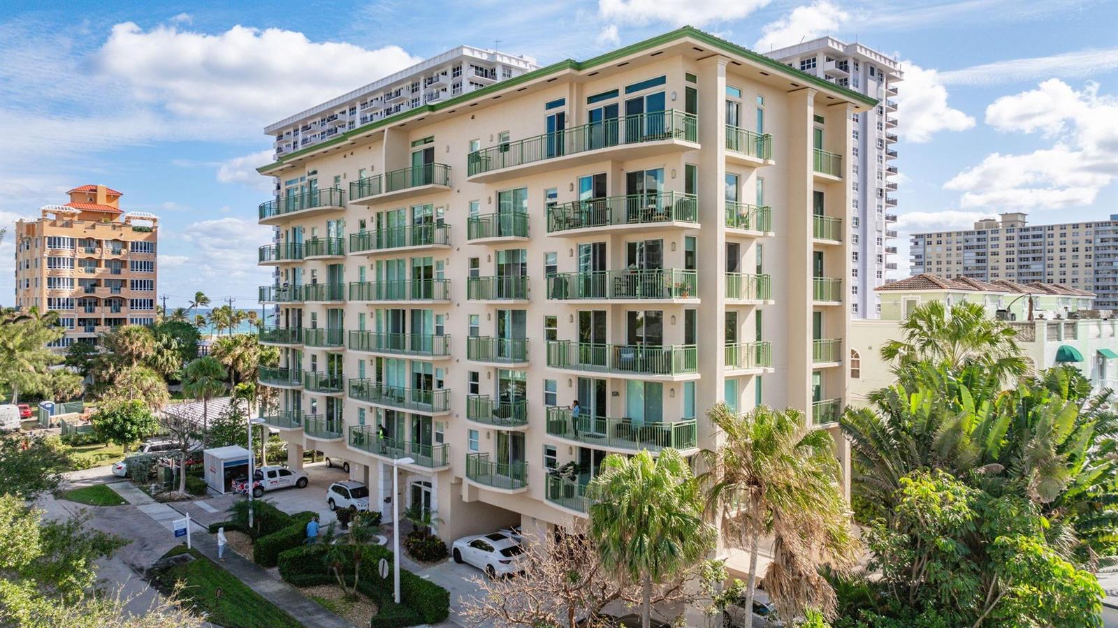 An exterior view of a multi-story apartment building with balconies and surrounding palm trees — 3210 NE 5th Street # 202, Pompano Beach FL 33062, POMPANO BEACH, FL