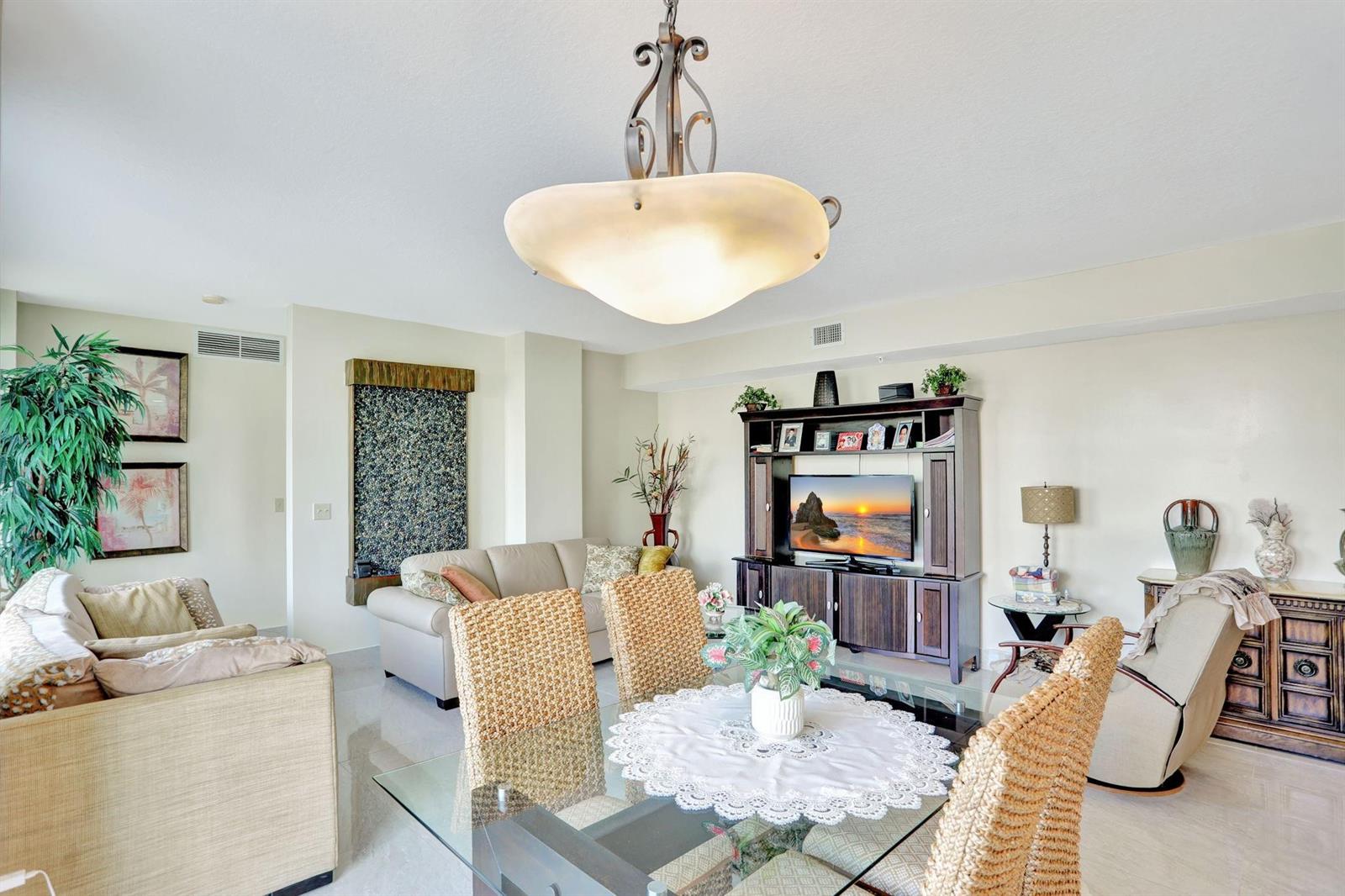 A living and dining area features a glass table, wicker chairs, and a wall fountain — 3210 NE 5th Street # 202, Pompano Beach FL 33062, POMPANO BEACH, FL