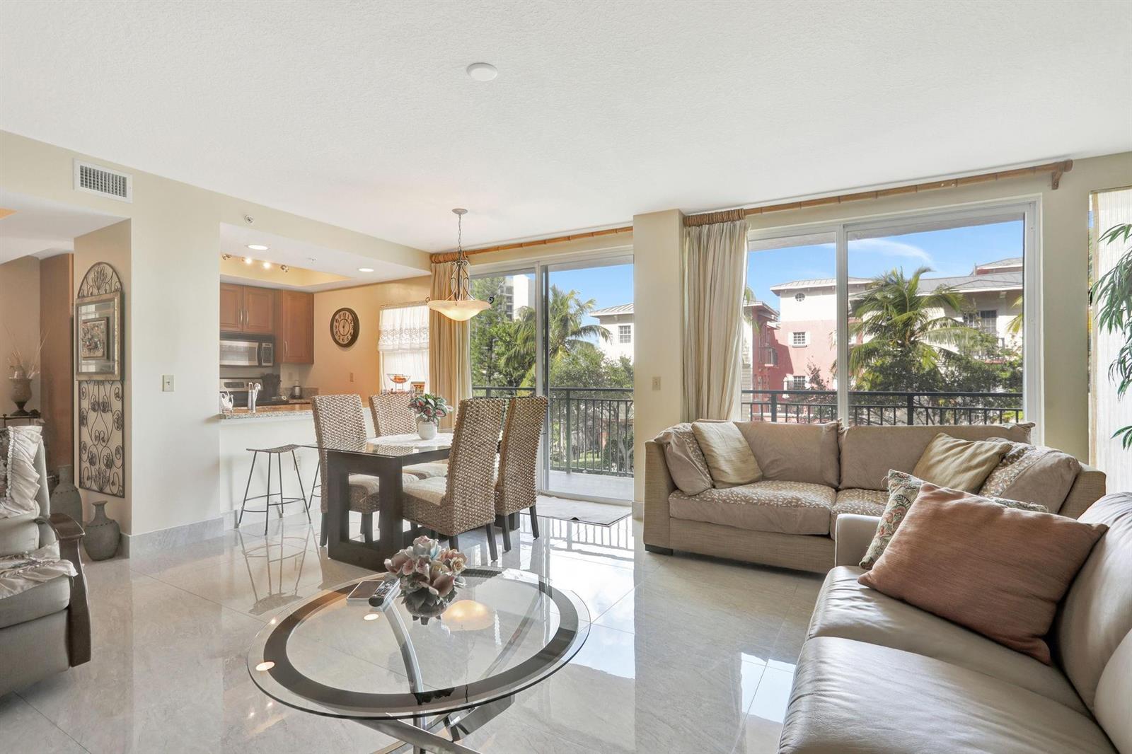 A bright living and dining area with tile floors, a glass table, and balcony access — 3210 NE 5th Street # 202, Pompano Beach FL 33062, POMPANO BEACH, FL