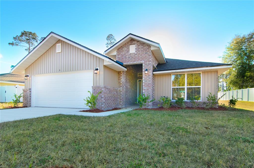 A single-story house features a brick-accented entryway, tan vertical siding, and a two-car garage — 33 FARNELL LANE, PALM COAST, FL