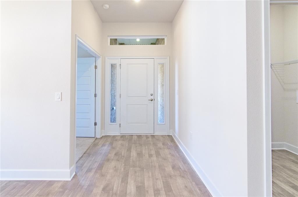 A bright entryway features light wood-look flooring, a white front door, and side windows — 33 FARNELL LANE, PALM COAST, FL