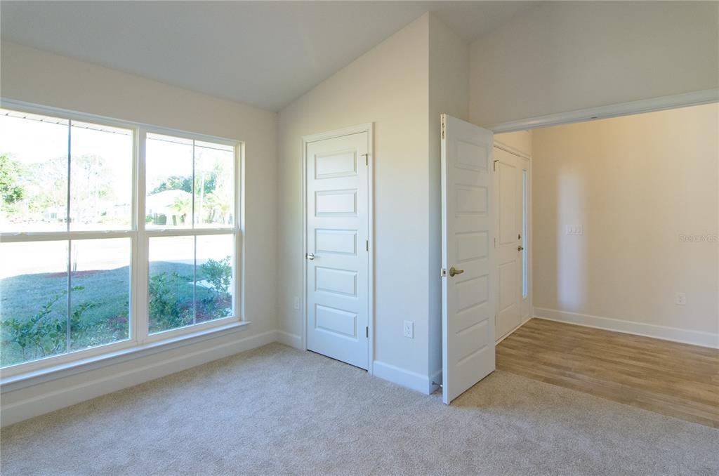 A room with beige carpet, a window, and an open door leading to a hallway — 33 FARNELL LANE, PALM COAST, FL