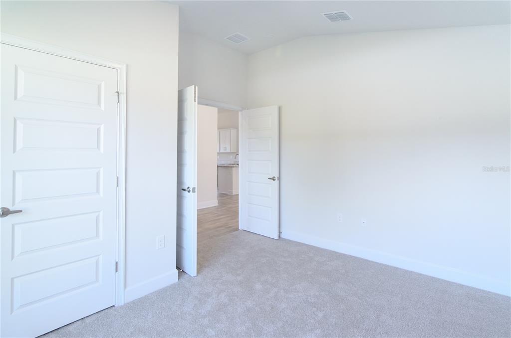 A carpeted room with white walls and two open doors leading to another area — 33 FARNELL LANE, PALM COAST, FL