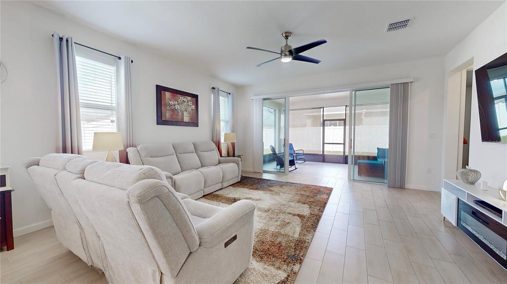 A living room features light-colored tile floors, a neutral sofa, and sliding glass doors — 2303 JAGGER LANE, EAGLE LAKE, FL