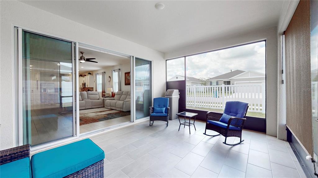 A covered patio with tiled flooring, two rocking chairs, and sliding glass doors to the interior — 2303 JAGGER LANE, EAGLE LAKE, FL