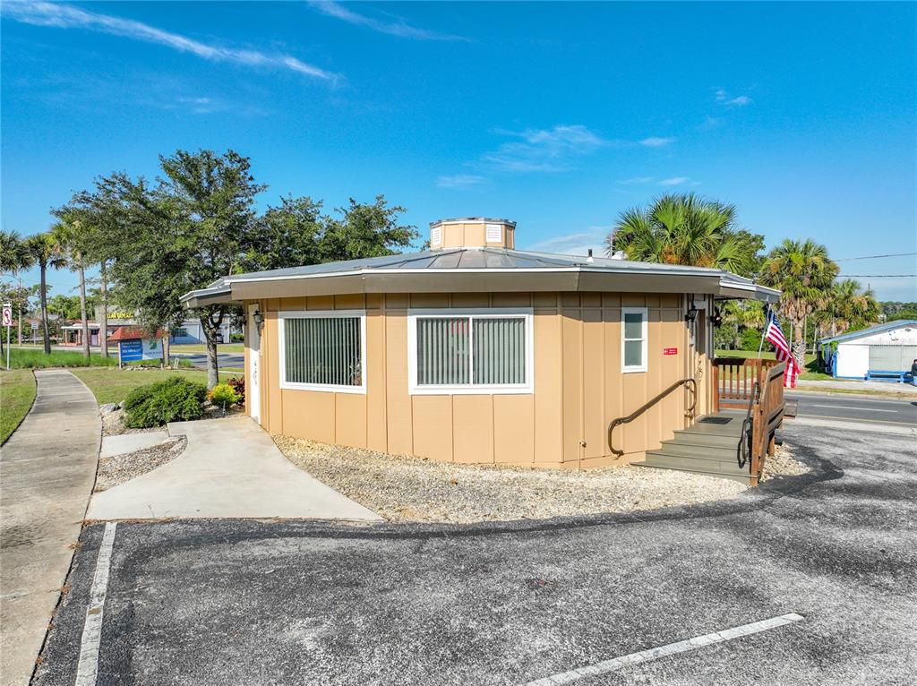 A tan, hexagonal-shaped commercial building with a metal roof and a small wooden entrance deck — 811 S BAY STREET, EUSTIS, FL