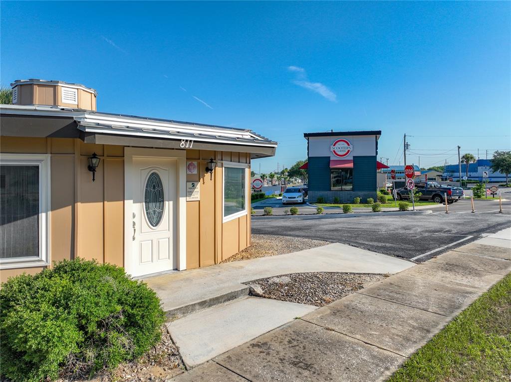 A tan building with a white door stands next to a Scooter's Coffee shop — 811 S BAY STREET, EUSTIS, FL