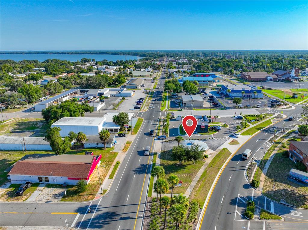 An aerial view shows a commercial property with a red location pin on a road — 811 S BAY STREET, EUSTIS, FL