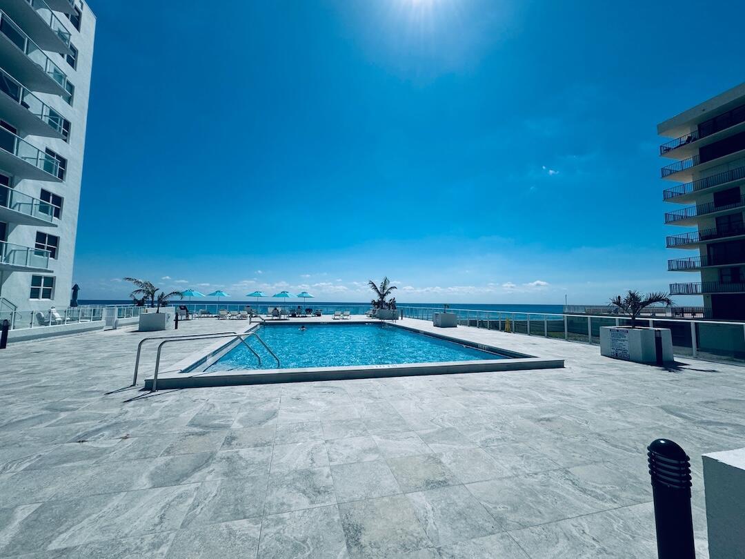An outdoor swimming pool sits on a stone patio between two high-rise buildings — 3450 S Ocean Boulevard # 5030, Palm Beach FL 33480, PALM BEACH, FL