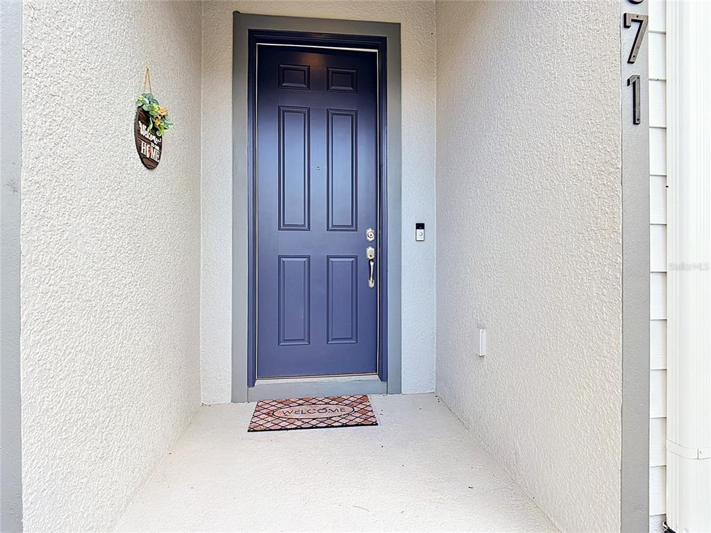 A dark blue front door is set within a recessed entryway with textured white walls — 371 CROSSINGS AVENUE, ST CLOUD, FL