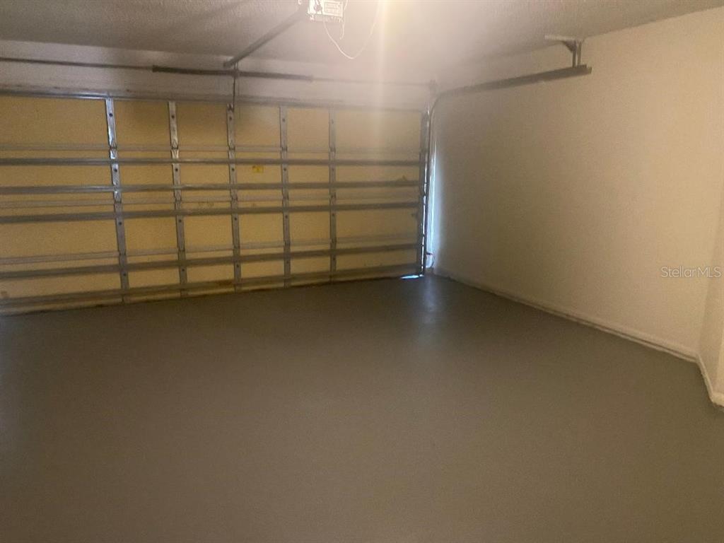 An empty garage with a concrete floor, white walls, and a sectional metal door — 1003 WINTERBERRY LANE, ORLANDO, FL