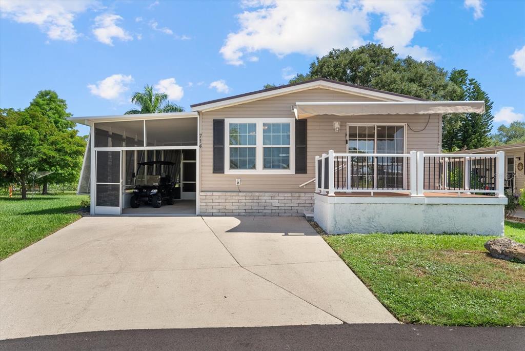 A single-story manufactured home features a screened carport, a front deck, and a concrete driveway — 714 FAIRMOUNT DRIVE, NORTH PORT, FL