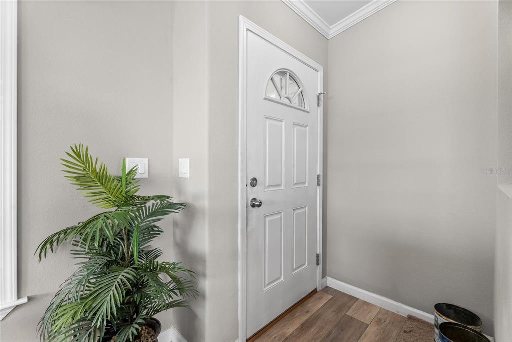 An entryway features a white front door, light gray walls, and wood-look flooring — 714 FAIRMOUNT DRIVE, NORTH PORT, FL