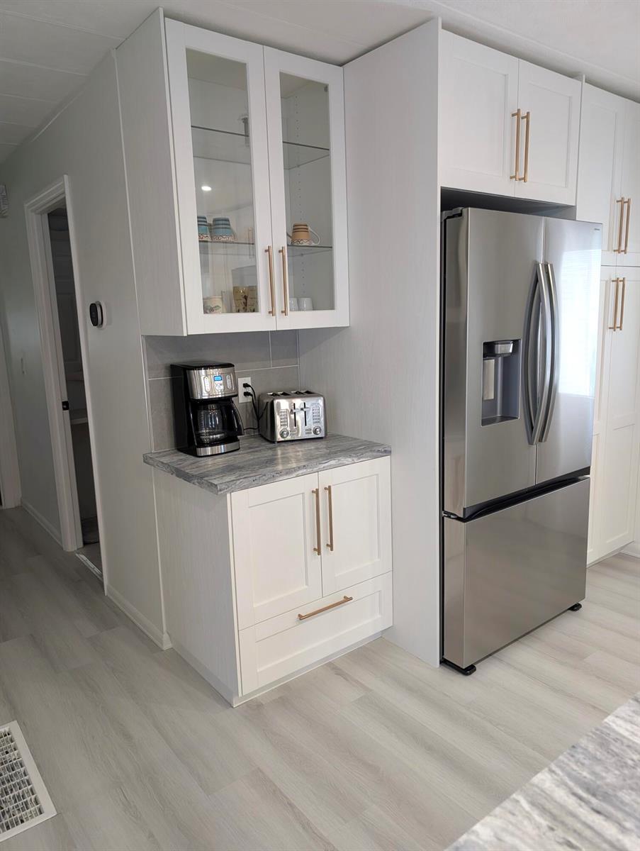 A kitchen area features white cabinetry, a stainless steel refrigerator, and a gray marble-patterned countertop — 37045 Exuma Bay, Boynton Beach FL 33436, BOYNTON BEACH, FL