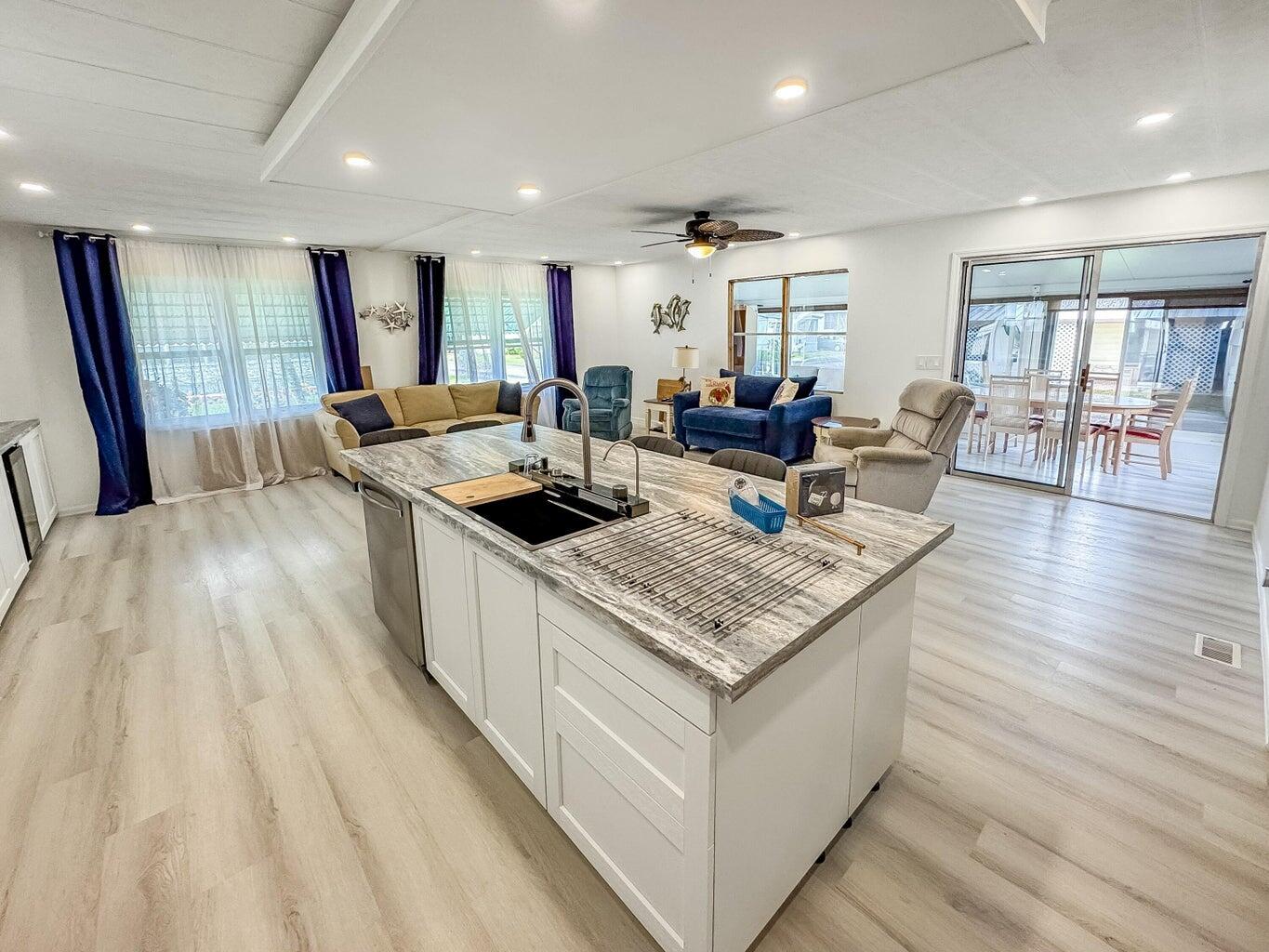 A kitchen island with a sink sits in an open-concept living area with light flooring — 37045 Exuma Bay, Boynton Beach FL 33436, BOYNTON BEACH, FL