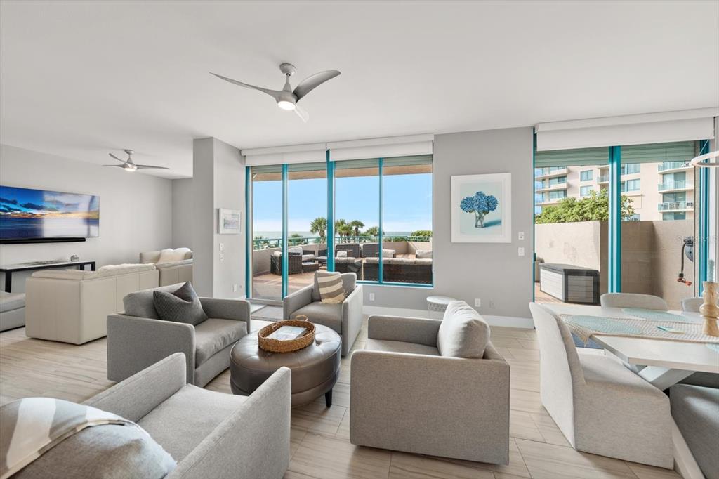A modern living and dining area features light tile floors, neutral furniture, and a balcony — 1560 GULF BOULEVARD UNIT 304, CLEARWATER, FL