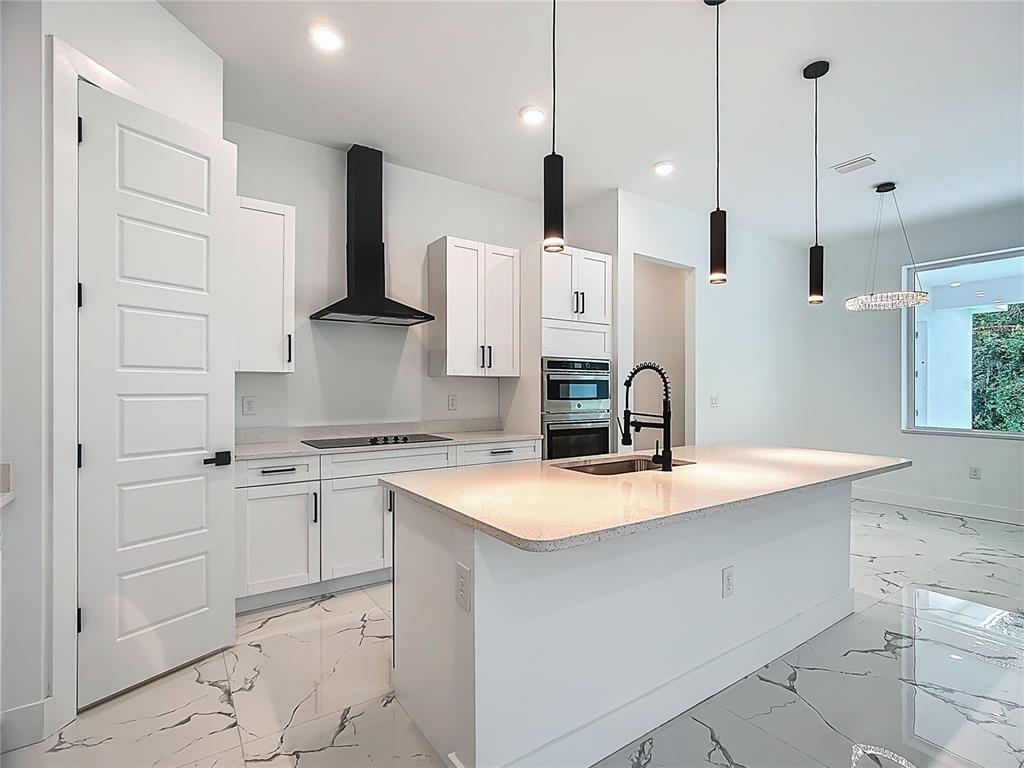 A modern kitchen features white cabinets, a central island, black fixtures, and marble-patterned tile flooring — 2105 DORMAN ROCK PLACE, PLANT CITY, FL
