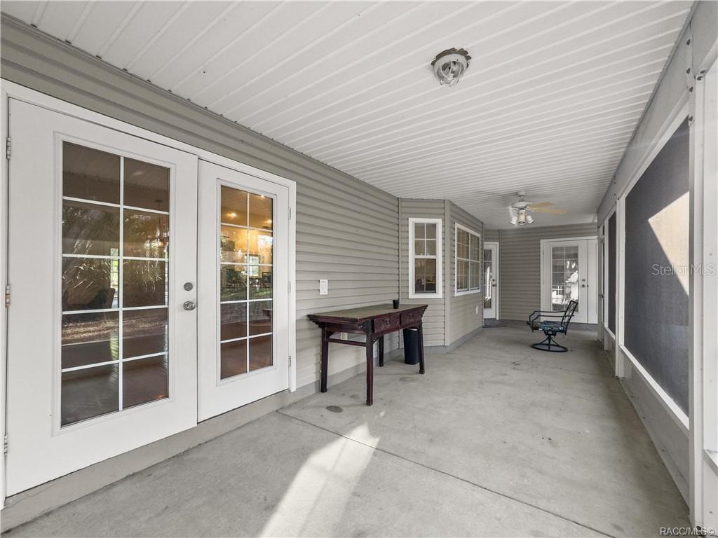 A covered outdoor patio features light gray siding, a concrete floor, and multiple glass doors — 10 PATRICIA ROAD, YANKEETOWN, FL