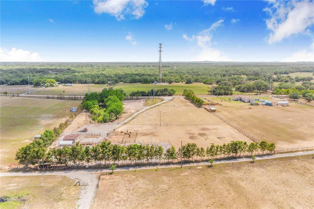 An aerial view shows a large, fenced rural property with trees, outbuildings, and a radio tower — LAKE HATCHINEHA ROAD, HAINES CITY, FL