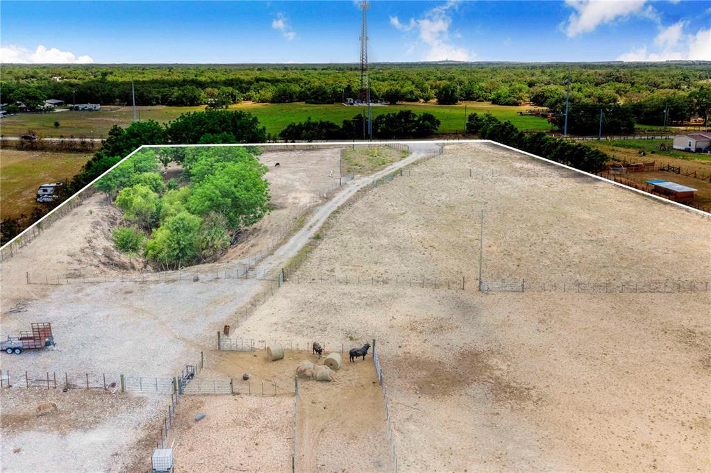 An aerial view shows a fenced rural property with a dirt driveway and livestock — LAKE HATCHINEHA ROAD, HAINES CITY, FL
