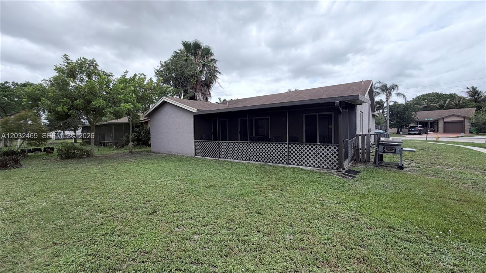 The exterior of a house features a screened-in porch with lattice skirting and a lawn — 5356 NW 93rd Ter, Sunrise FL 33351, SUNRISE, FL