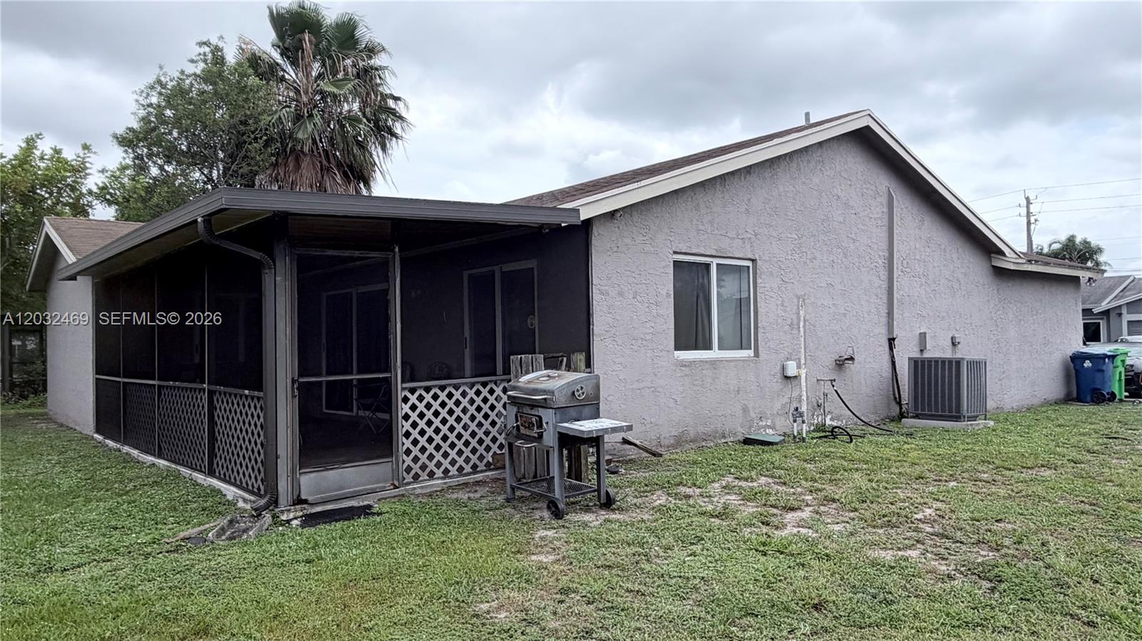 The exterior of a house features a screened-in porch, a grill, and an air conditioning unit — 5356 NW 93rd Ter, Sunrise FL 33351, SUNRISE, FL