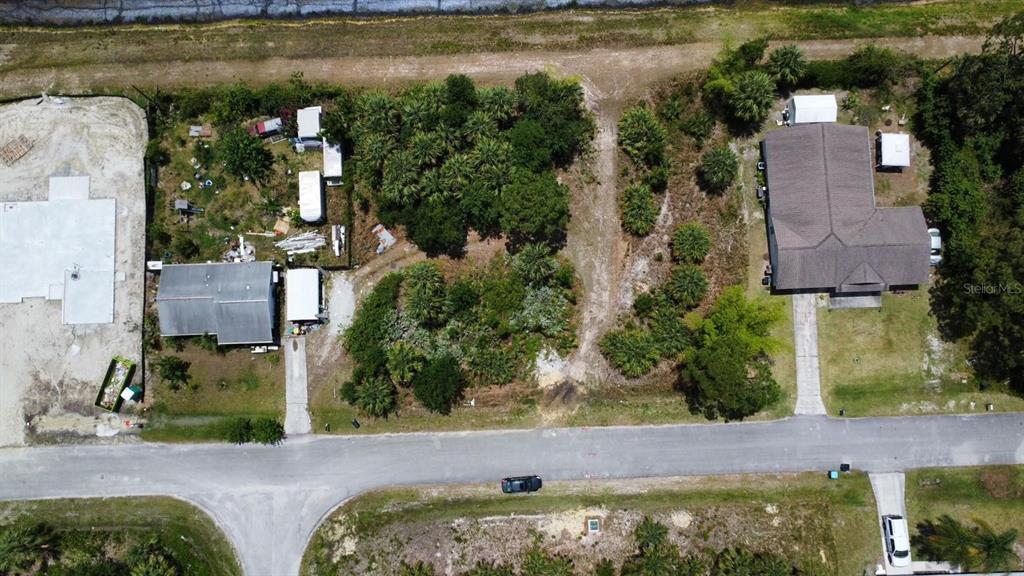 An aerial view shows two houses separated by a wooded lot along a paved road — 480 TRUMAN STREET SW, PALM BAY, FL