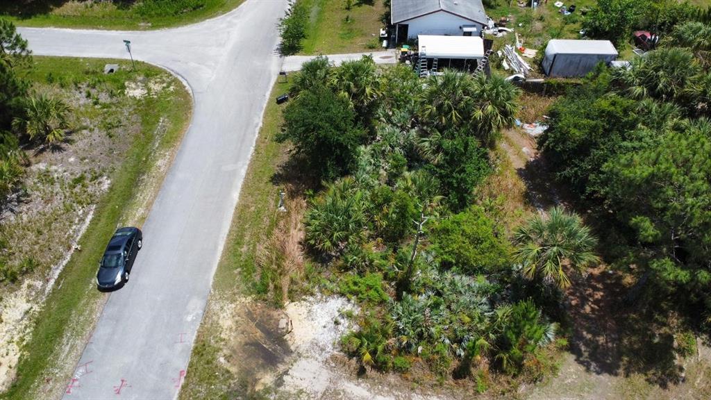 An aerial view shows a vacant, wooded lot next to a paved road and house — 480 TRUMAN STREET SW, PALM BAY, FL