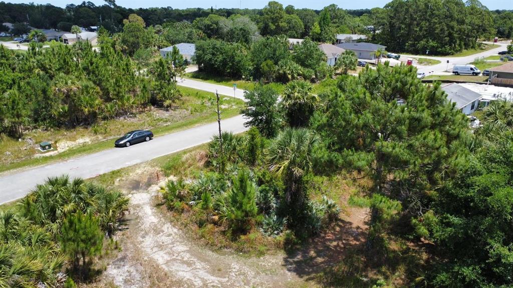 An aerial view shows a vacant, wooded residential lot next to a paved road — 480 TRUMAN STREET SW, PALM BAY, FL