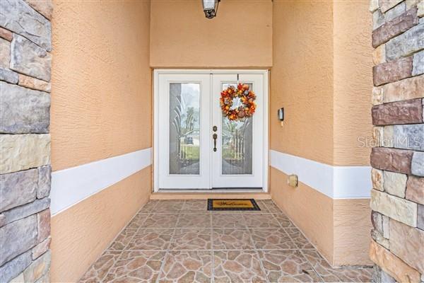 A front entryway features double glass doors, a stone-tiled floor, and stone-accented exterior walls — 4190 SW 103RD STREET ROAD, OCALA, FL