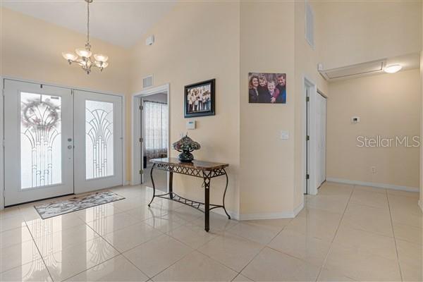 A bright foyer features light-colored tile flooring, a decorative console table, and a chandelier — 4190 SW 103RD STREET ROAD, OCALA, FL