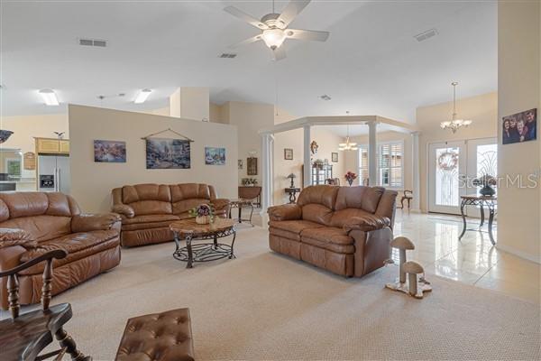 A spacious living room features brown leather sofas, a ceiling fan, and tile flooring — 4190 SW 103RD STREET ROAD, OCALA, FL