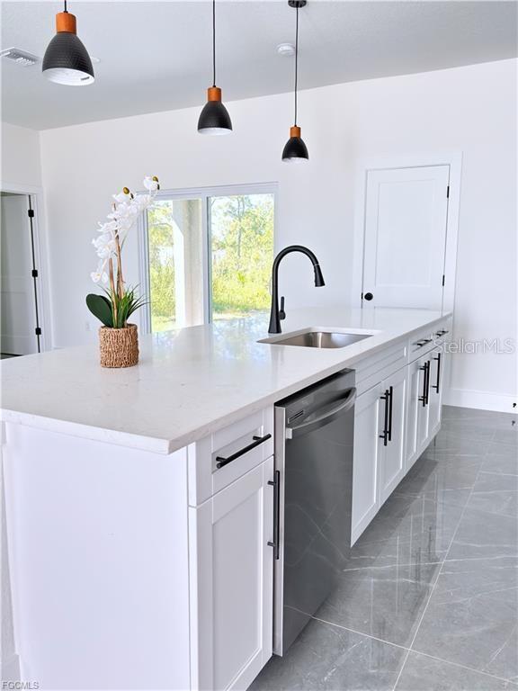 A kitchen island with a stainless steel dishwasher, sink, and white cabinets sits on tiled flooring — 842 GIORGIO AVENUE S, LEHIGH ACRES, FL