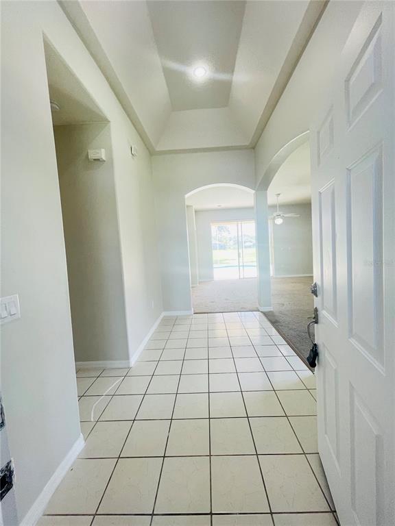 An entryway with light-colored tile flooring leads to a living area with a pool view — 1738 GOLFVIEW DRIVE, KISSIMMEE, FL