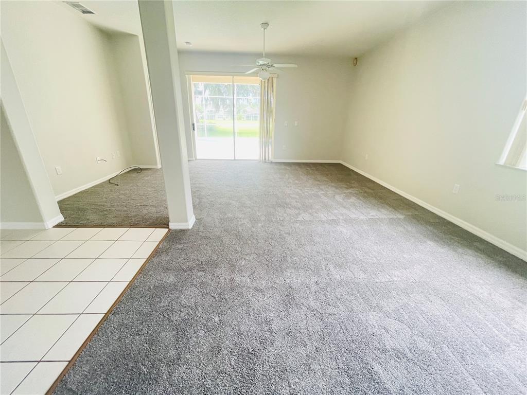 A carpeted living room features a ceiling fan and sliding glass doors leading to a pool — 1738 GOLFVIEW DRIVE, KISSIMMEE, FL