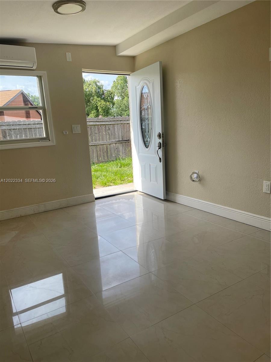 A room with light-colored tile flooring, a white door, and a window overlooking a yard — 4617 Navarre Ave # B, Sebring FL 33872, SEBRING, FL