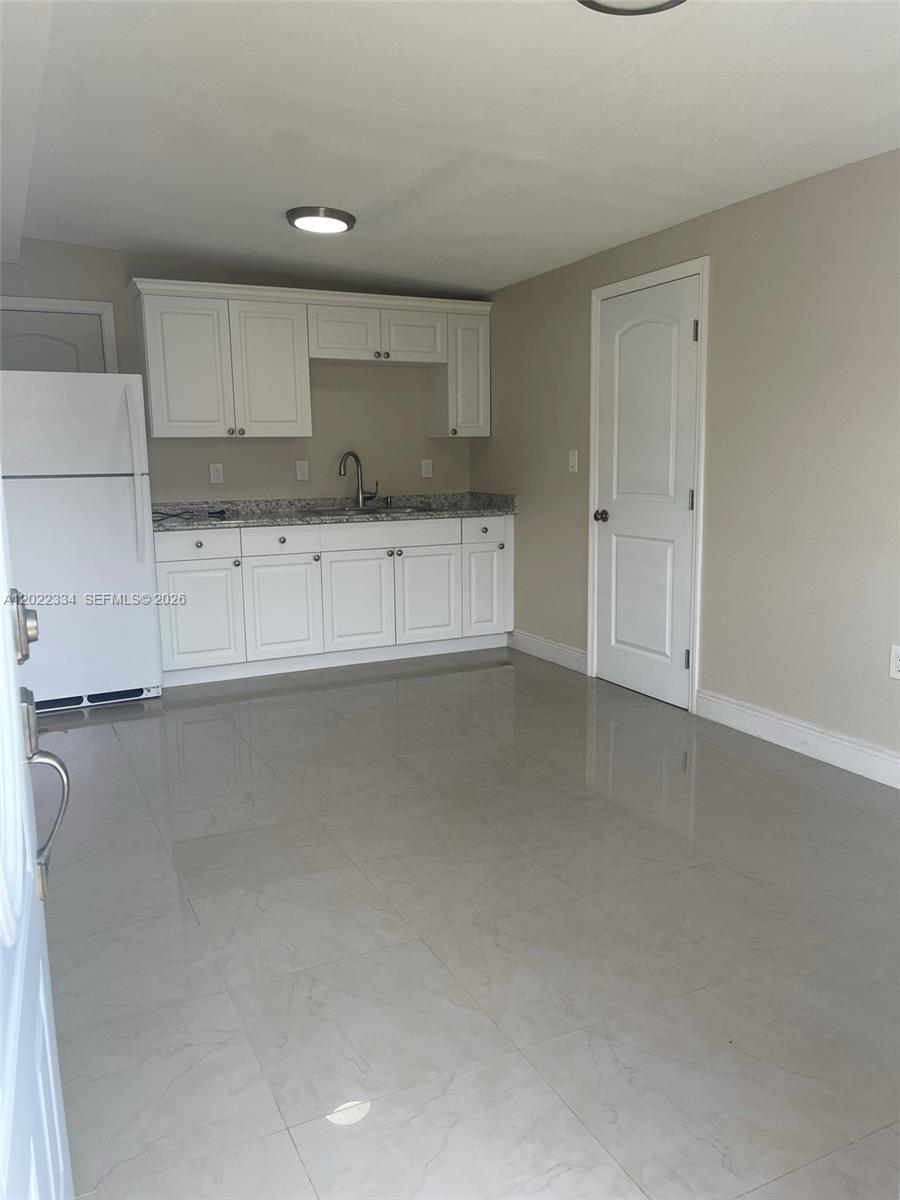 A kitchen features white cabinets, granite countertops, a white refrigerator, and light-colored tile flooring — 4617 Navarre Ave # B, Sebring FL 33872, SEBRING, FL