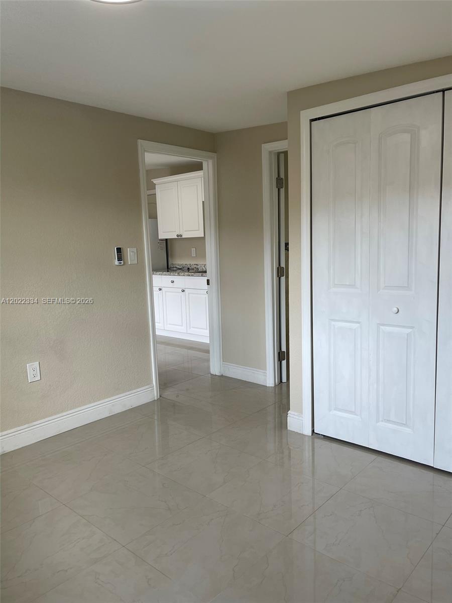 A room with light-colored tile flooring, beige walls, and white closet doors — 4617 Navarre Ave # B, Sebring FL 33872, SEBRING, FL
