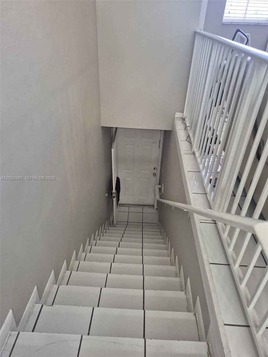 A staircase with white tiled steps leads down to a white door — 7818 W 34th Ln # 201, Hialeah FL 33018, HIALEAH, FL