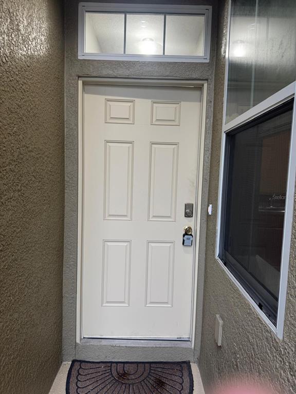 A beige six-panel front door with a transom window and a lockbox sits in an entryway — 2121 BROADWAY VIEW AVENUE, BRANDON, FL