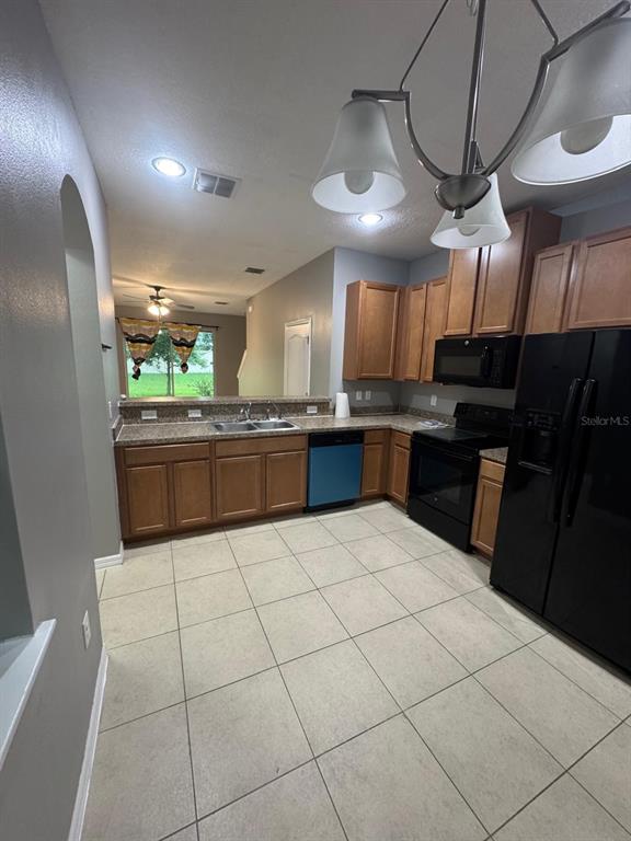 A kitchen with wood cabinets, granite countertops, tile flooring, and black appliances — 2121 BROADWAY VIEW AVENUE, BRANDON, FL