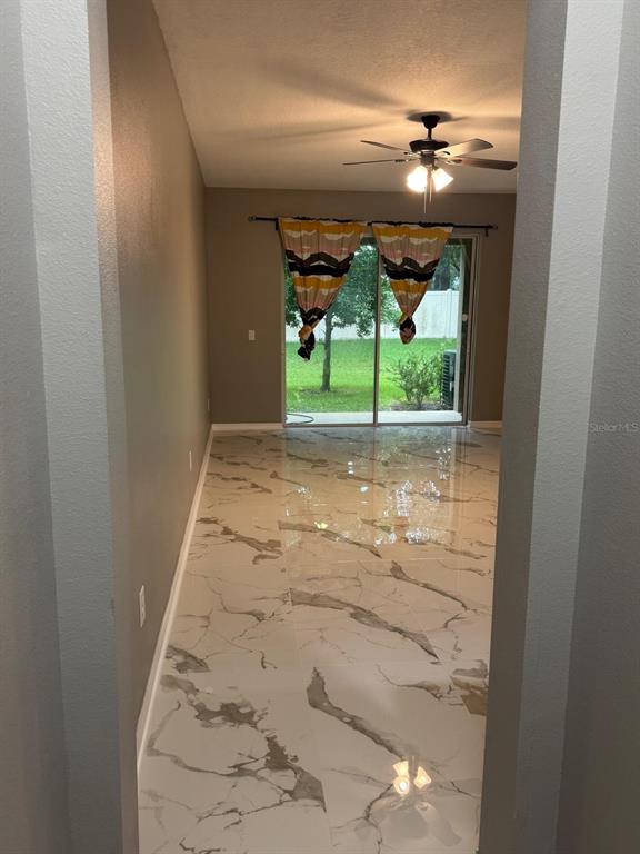 A room with white marble-look tile flooring and sliding glass doors leading to a backyard — 2121 BROADWAY VIEW AVENUE, BRANDON, FL