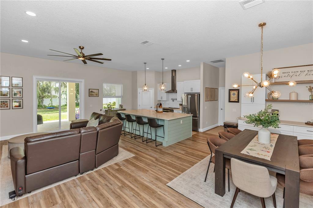 An open-concept living area features a kitchen with a green island, dining space, and sofa — 1530 PERIWINKLE AVENUE, DELAND, FL