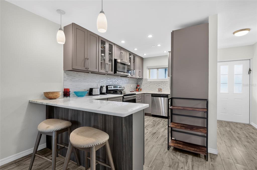 A kitchen with gray cabinets, a white countertop breakfast bar, and stainless steel appliances — 2155 WOOD STREET UNIT A22, SARASOTA, FL