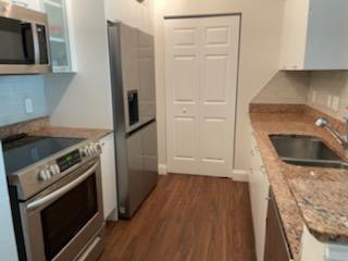 A kitchen features stainless steel appliances, granite countertops, white cabinets, and wood-look flooring — 625 Casa Loma Boulevard # 705, Boynton Beach FL 33435, BOYNTON BEACH, FL