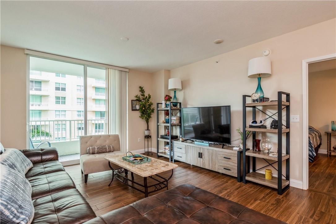 A living room features a leather sofa, a television console, and a balcony with views — 625 Casa Loma Boulevard # 705, Boynton Beach FL 33435, BOYNTON BEACH, FL