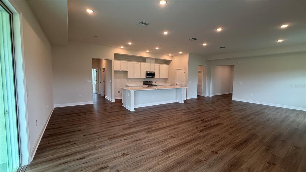 An open-concept kitchen with white cabinets and a large island overlooks a spacious living area — 4366 WINESAP WAY, LAKELAND, FL