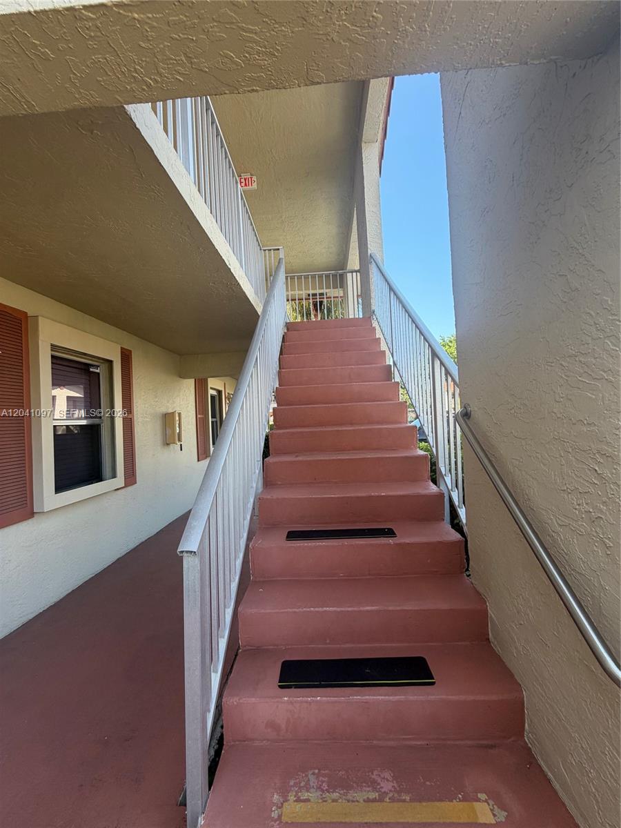 An outdoor concrete staircase with metal railings leads to an upper-level walkway — 3031 Holiday Springs Blvd # 7, Margate FL 33063, MARGATE, FL